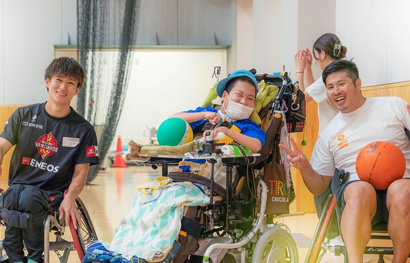 スタッフと車いすの子どもがバスケットボールで交流する様子