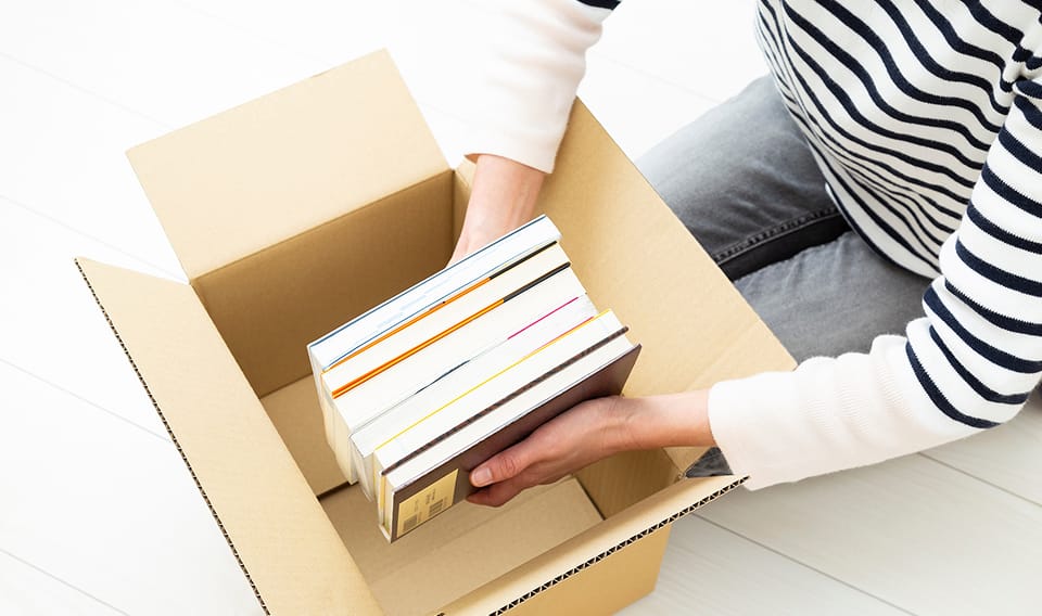 古本で寄付のイメージ：段ボールに本を詰める人