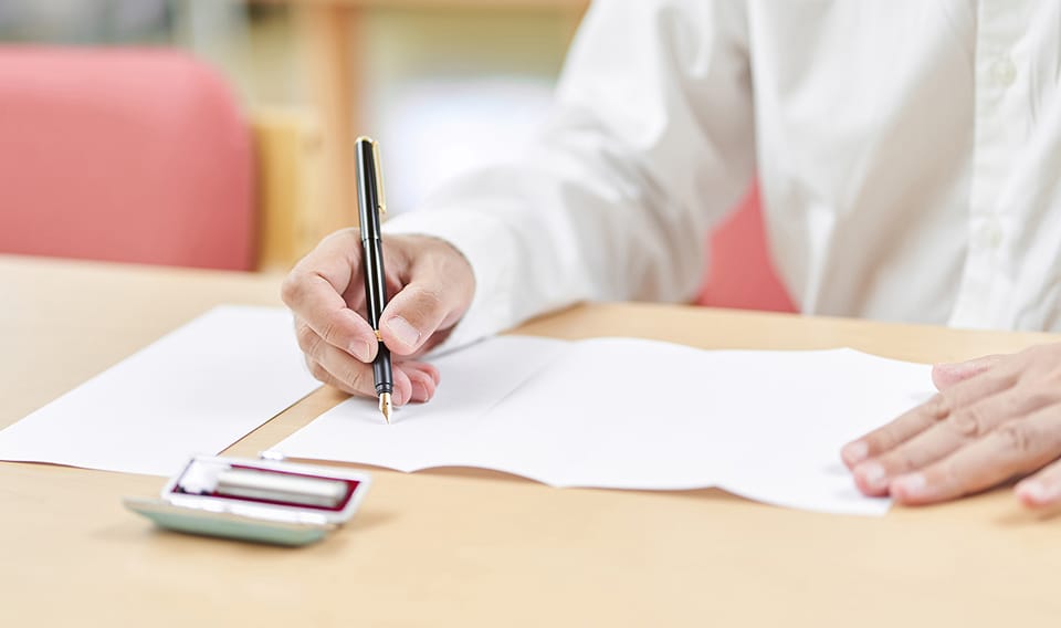 遺贈寄付のイメージ：書類に記入する高齢者の手元